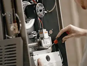 Furnace repair technician inspecting internal components and wiring in Hoboken, NJ