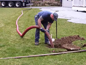 Septic pumping technician servicing a residential septic tank with a vacuum hose in Hoboken, NJ