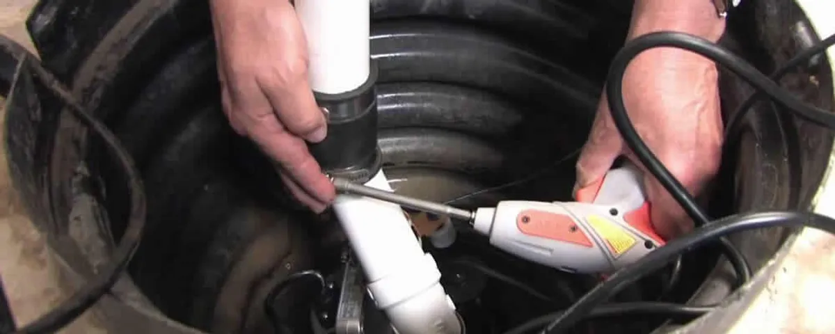 Sump pump installation technician connecting PVC discharge piping in Hoboken, NJ